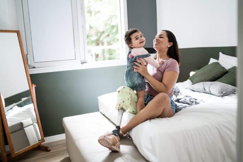 A woman with a prosthetic leg holding her baby.