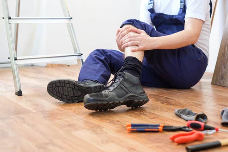 An independently contracted construction worker holds his leg in pain after accidentally injuring himself.