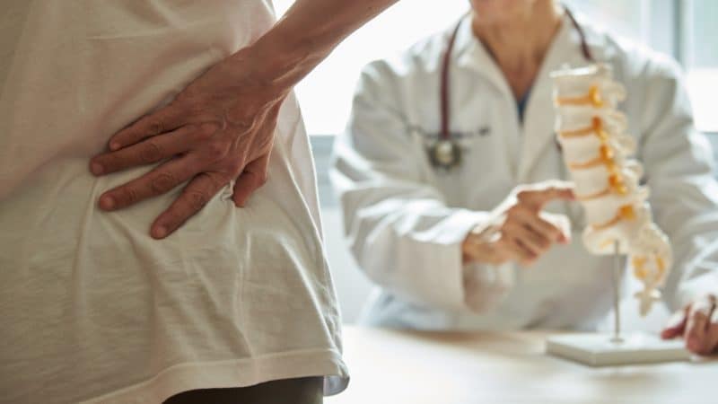 A man with a severe back injury in Southern California talks with his doctor about his spine.