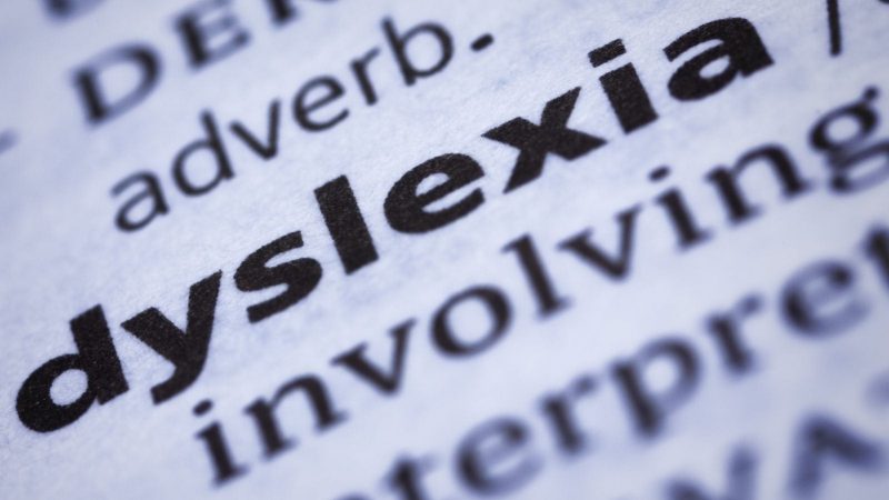 Close-up of the word "dyslexia" in bold print from a dictionary, with surrounding text slightly blurred.