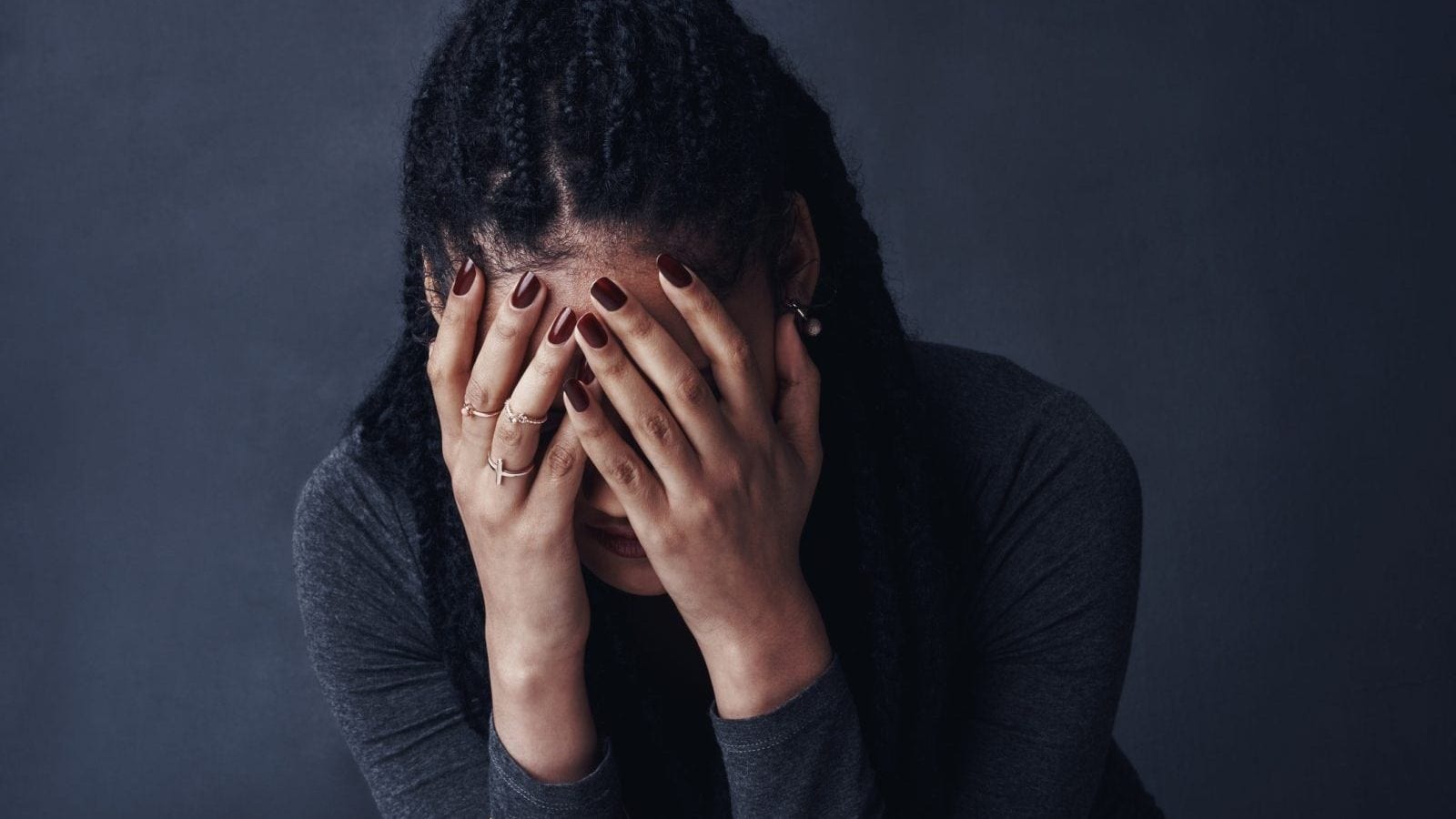 A woman covering her face with her hands, appearing distressed.