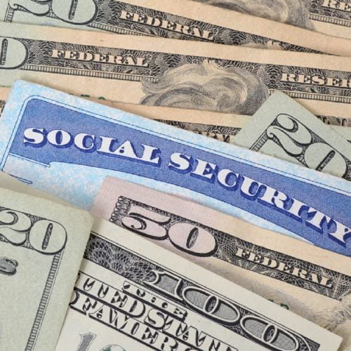 A Social Security card partially tucked between $20, $50, and $100 bills.