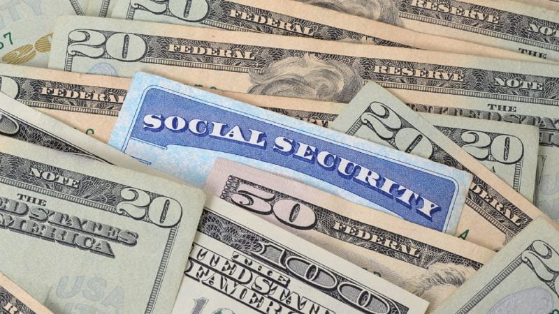A Social Security card partially tucked between $20, $50, and $100 bills.