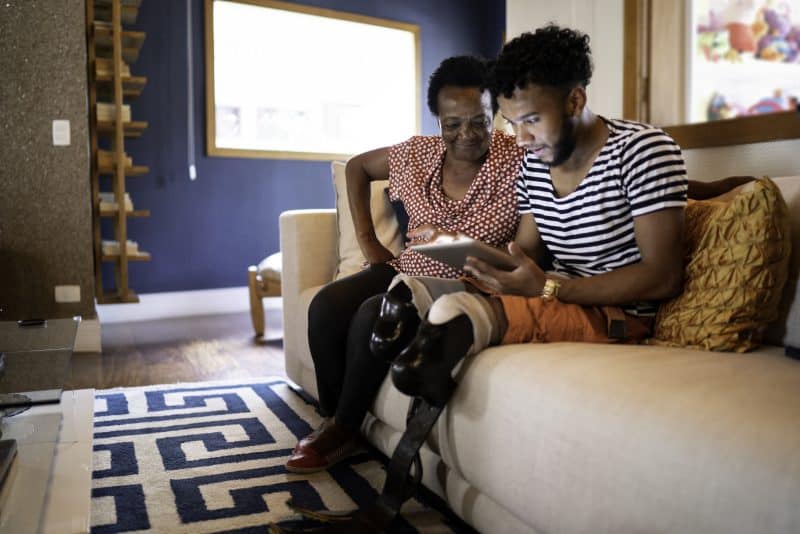 A man with two prosthetic legs doing research on a tablet.