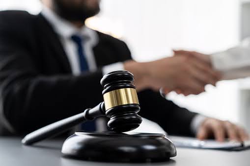 A Supplemental Security Income lawyer in Whittier shakes hands with his client. A gavel and sound block sit in the foreground.