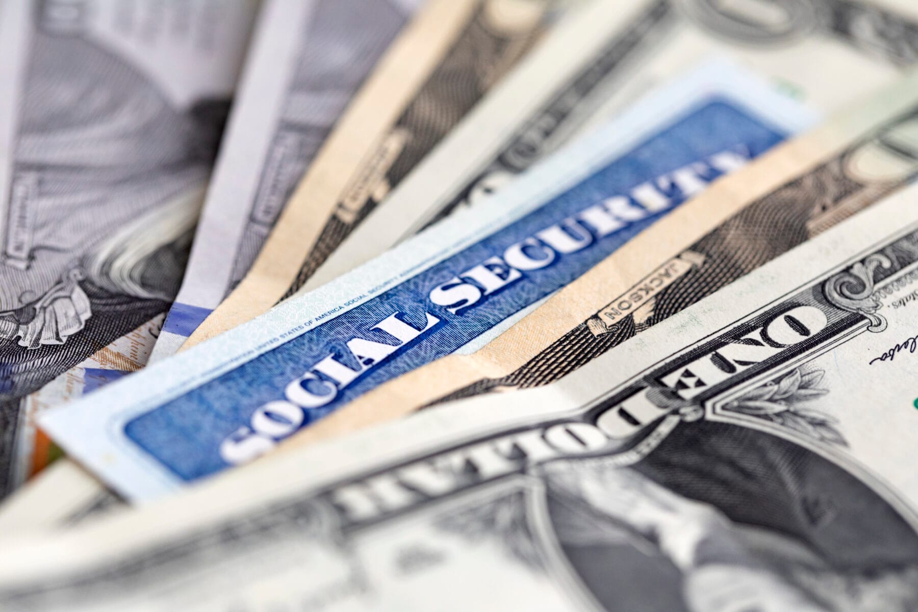 A social security card lying in a stack of money.